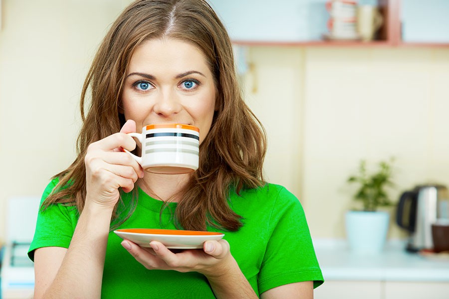 Ragazza beve una tazza di caffè verde