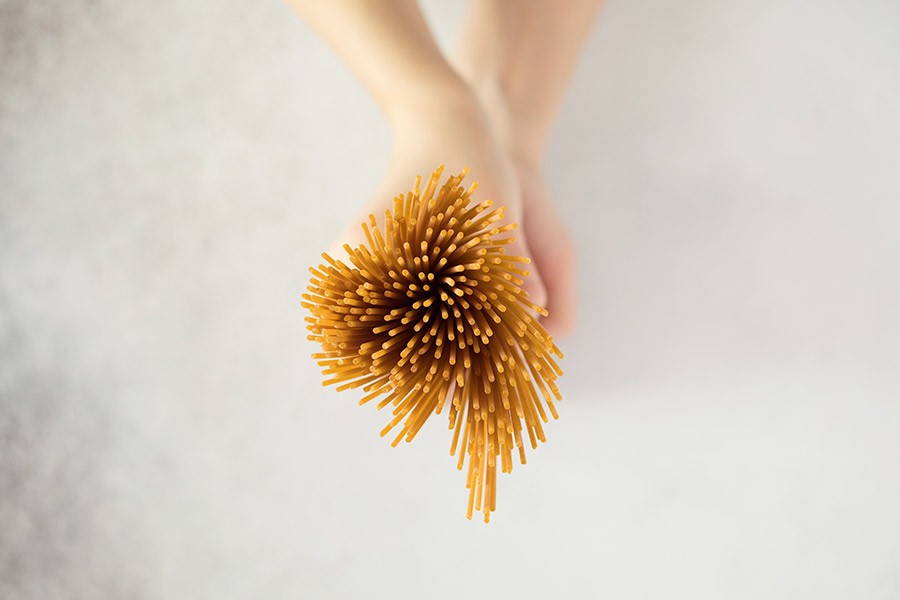 Donna tiene in mano un mucchio di spaghetti integrali per la sua dieta bilanciata