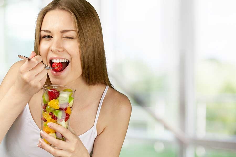 giovane donna mangia una macedonia di frutta